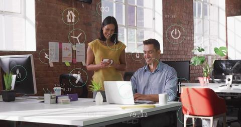 Young professionals collaborating over laptop and coffee in modern brick loft office