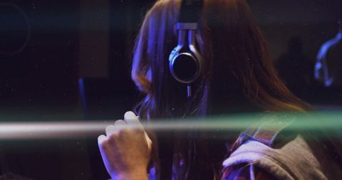 Singer in recording studio with headphones and microphone