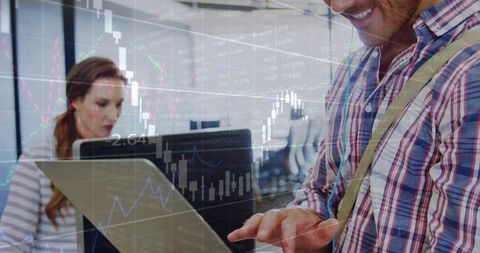 Man Using Laptop with Financial Charts Overlay in Modern Open Office Collaboration