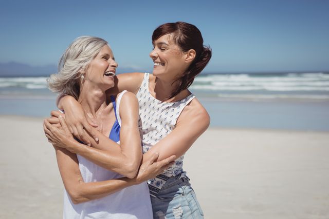 Happy woman with her mother standing at beach during sunny day