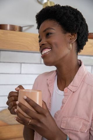 Smiling Woman Holding Coffee Mug in Cozy Kitchen Environment