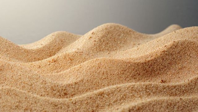 Macro sand dune ridges creating soft wave texture in warm beige granular close-up