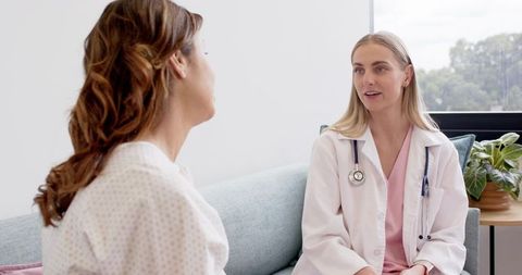 Female clinician consulting with patient on couch in bright clinic consultation room
