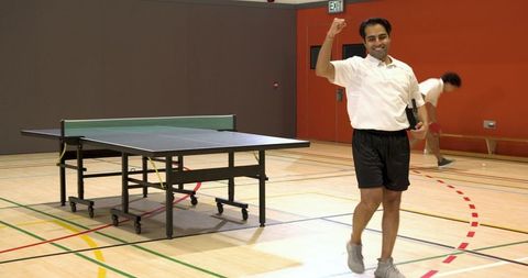 Celebrating Victory on Indoor Ping Pong Court with Diverse Male Players