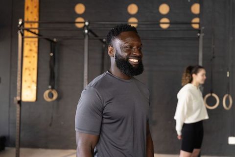 Smiling trainer and female athlete standing in functional fitness studio with rings and pull-up rig