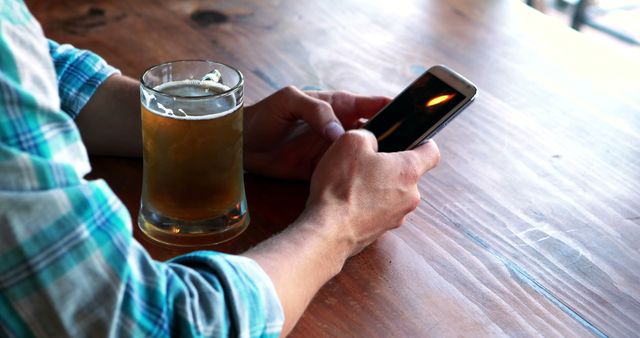 Man using mobile phone while having beer in pub