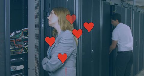 Businesswoman leaning in server room with colleague nearby