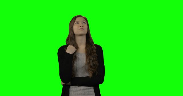 Smiling young woman looking around against green screen