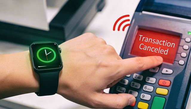 Smartwatch-wearing hand tapping pos terminal displaying transaction canceled and nfc pulse