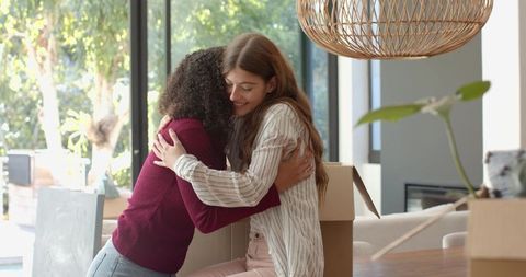 Diverse Friends Embracing While Unpacking in New Home