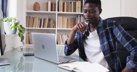 Focused Man Studying with Laptop in Modern Workspace