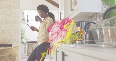 Woman leaning at kitchen counter sipping coffee and checking smartphone with colorful overlay