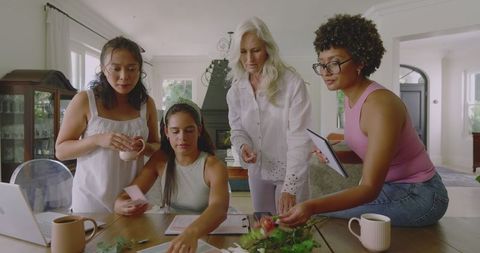 Diverse women planning wedding at home around wooden table