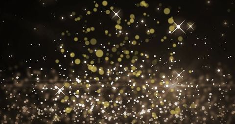 Shimmering Gold and White Bokeh Sparkling with Star Flares on Dark Backdrop