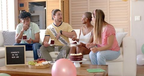 Friends celebrating job success with cake at home
