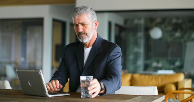 Senior Businessman Working on Laptop in Modern Office with Glass of Water - Download Free Stock Images Pikwizard.com