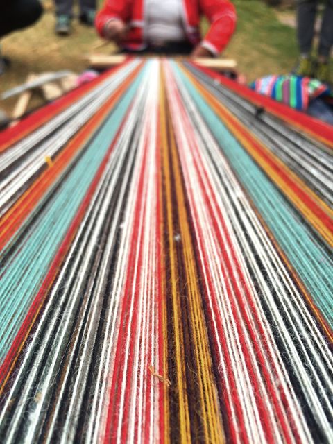 Colorful threads tightly aligned on a loom during traditional weaving process, showcasing intricate pattern and artisanal skill. Use in articles on traditional crafts, textile design, cultural heritage, handmade products, and artisan craftsmanship.