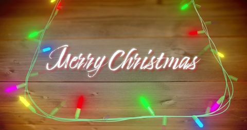 Merry Christmas Text with Colorful Fairy Lights on Wooden Background