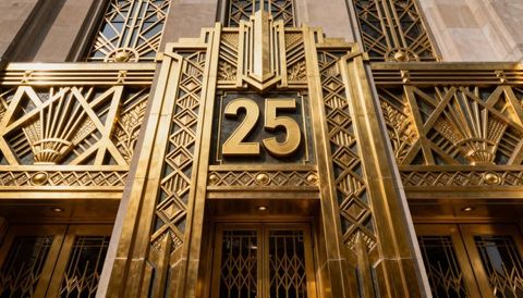 Gilded art deco entrance showing number 25 with ornate sunburst and geometric metalwork