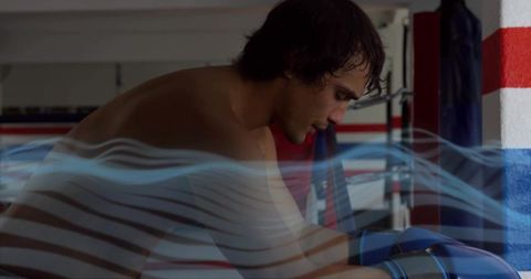 Shirtless boxer leaning on ropes wearing blue gloves with motion streaks, intense focus