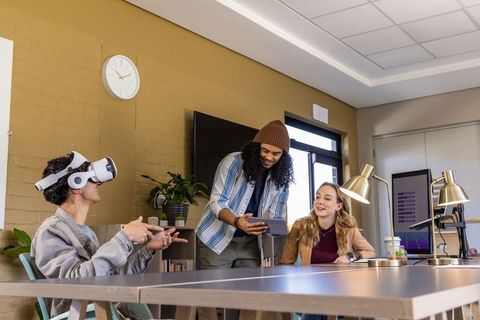 Diverse team testing vr prototype while collaborating over tablet in modern office