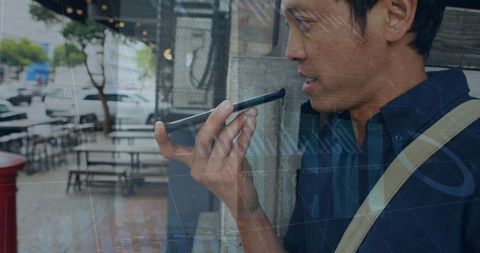 Asian Man Communicating Through Smartphone on City Street