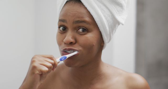 Happy african american woman brushing teeth in bathroom. domestic lifestyle, spending free time at home.