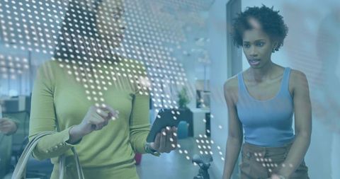 Two professionals collaborating in modern office by glass wall with smartphone overlay