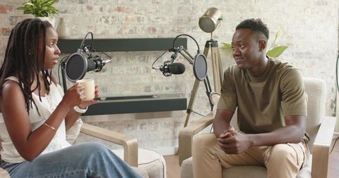 African american hosts recording conversational podcast in cozy studio with microphones