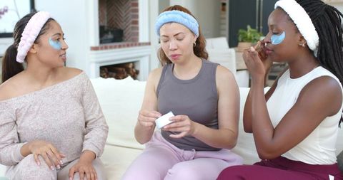 Trio applying under-eye gel patches during cozy home skincare session