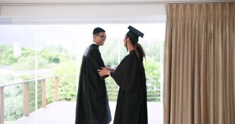 Happy Asian Couple in Graduation Attire Celebrating Achievements at Home