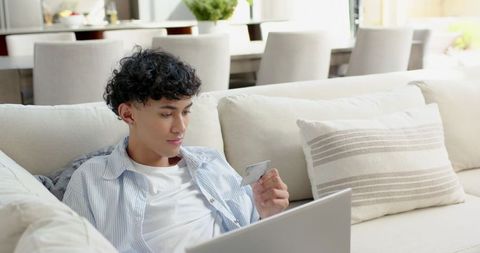 Young Asian Man Online Shopping in Cozy Minimalist Living Room