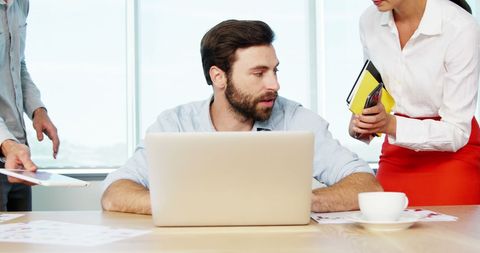 Stressed Businessman Working at Desk with Team Discussion - Download Free Stock Images Pikwizard.com