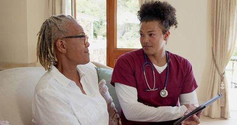 Senior Woman Engaging with Nurse for Healthcare Consultation at Home