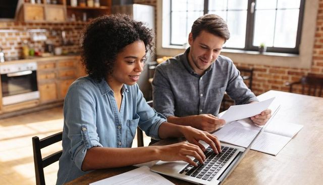 Young couple managing household finances and paperwork together at cozy loft kitchen table