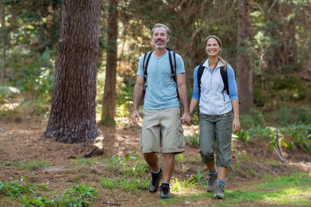 Hiker couple holding hands while hiking in forest
