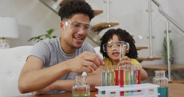 Happy biracial man and his son making chemistry experiments. domestic life, spending time at home.