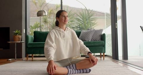 Young Woman Meditating with Earphones in Cozy Modern Living Room