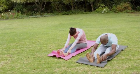 Diverse Fitness Partners Stretching on Lawn with Yoga Mats