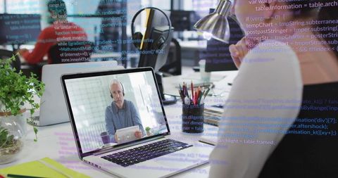 Video conferencing and coding collaboration on laptop in modern bright open-plan office