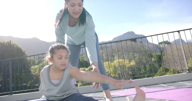 Mother helping daughter with yoga stretch on balcony with mountain view - Download Free Stock Images Pikwizard.com