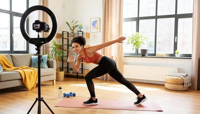 Home fitness instructor recording hiit lunge workout with ring light and camera