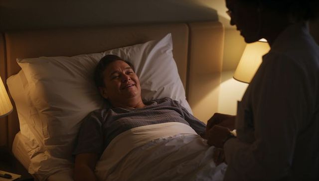 Nighttime home care comforting senior man in bed receiving gentle bedside personal care