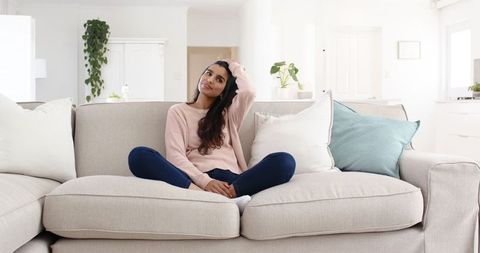 Relaxed Woman Sitting on Sofa in Bright Minimalist Living Room