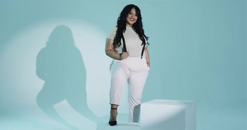 Confident Woman Posing in Stylish Outwear under Teal Spotlight