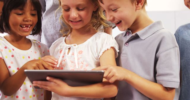 Group of children playing and exploring on a tablet together. They are smiling and enjoying the activity. Can be used for education, technology, childhood recreation, and promoting teamwork and digital learning.
