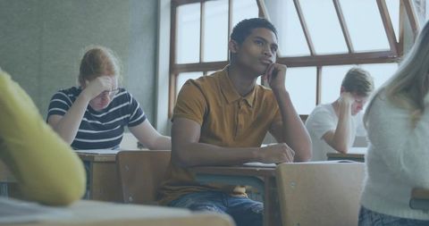 High School Student Daydreaming at Desk During Exam, Classroom Focus and Introspection