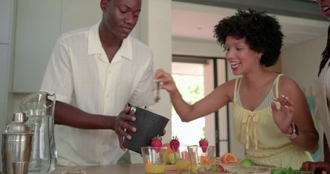 African american friends preparing tropical fruit drinks with fresh strawberries and ice