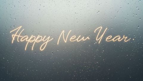 Neon happy new year script glowing on rainy window with bokeh lights