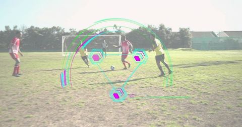 Dribbling striped jersey player controlling soccer ball on worn grass pitch, team play